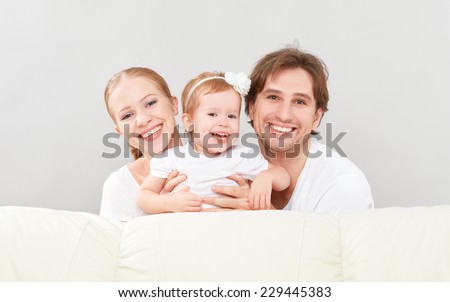 happy family mother, father, child baby daughter at home on the sofa playing and laughing
