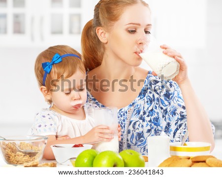 happy family mother and baby daughter  child girl at breakfast: biscuits with milk