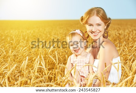 happy family in summer nature. Mother and baby daughter laugh, hug, play in the wheat field