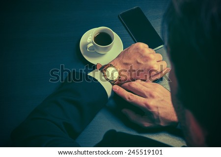phone and a cup of coffee in the hands of a businessman. stylish business still life in dark colors