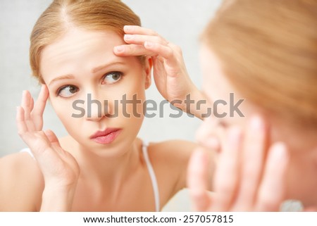 young beautiful healthy woman  frightened saw in the mirror acne and wrinkles