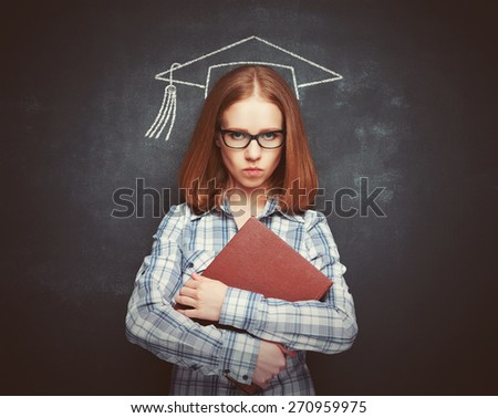 student girl in cap, glasses and a book at the blackboard