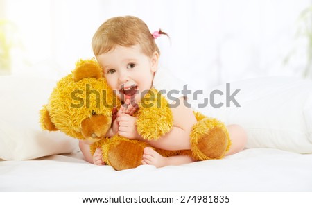 the cute little child girl hugging teddy bear in bed