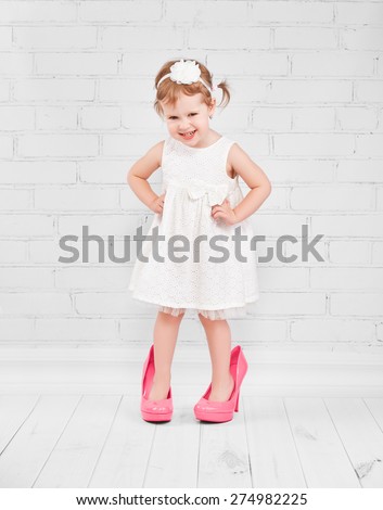 little girl fashionista in her mother\'s big pink heeled shoes