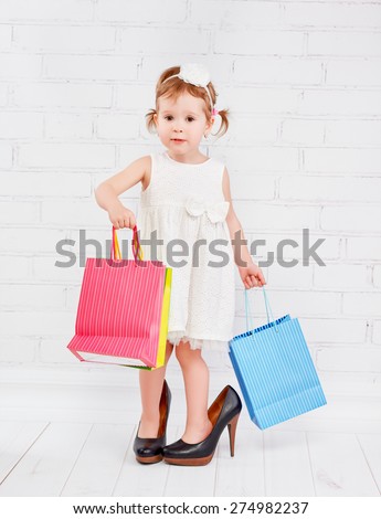 funny little girl fashionista in big lady heeled shoes went on shopping