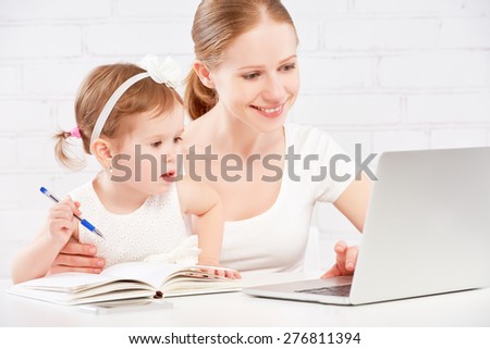 happy family mother and child baby daughter at home working on the computer