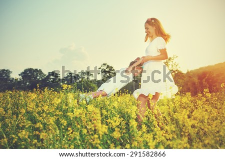 happy family plays in summer meadow, mother and little daughter girl child  with yellow flowers