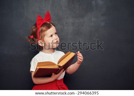 funny happy little girl schoolgirl with a book from the blackboard