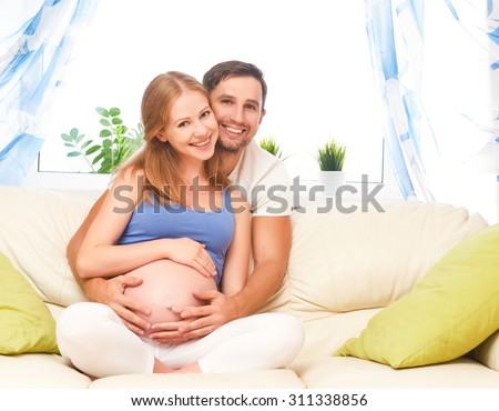 happy family in anticipation of the birth of the baby. Pregnant woman and her husband on the sofa at home