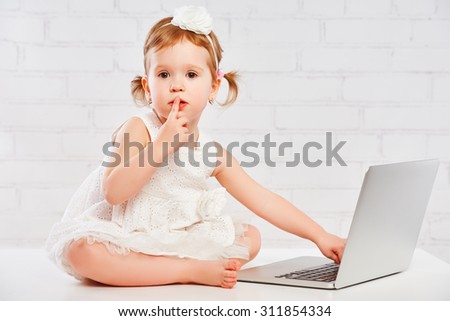 little child baby girl works at the computer at home