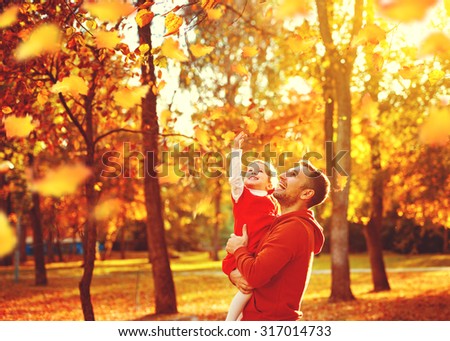 Happy family father and child daughter on a walk in the autumn leaf fall in park
