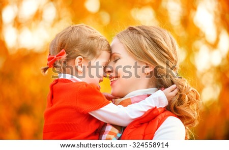 happy family. mother and child little daughter play kissing on autumn walk in nature outdoors