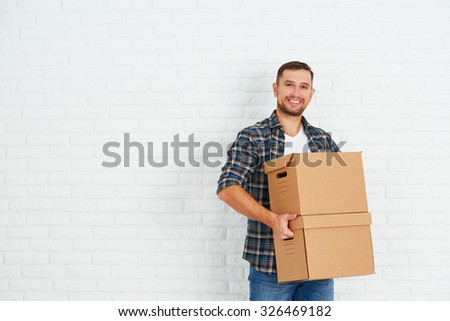 moving to a new apartment. Young happy man with cardboard boxes around the white brick wall