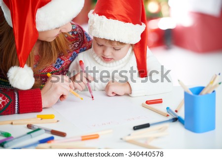 happy family mother and baby child daughter  write a letter to Santa Claus on Christmas Eve