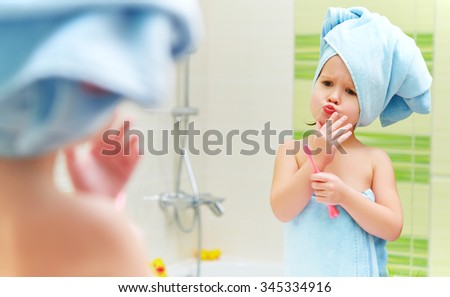 funny little girl cleans teeth with a toothbrush in the bathroom