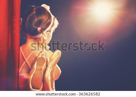 little child girl ballerina ballet dancer on the stage in red side scenes and looking in odeum