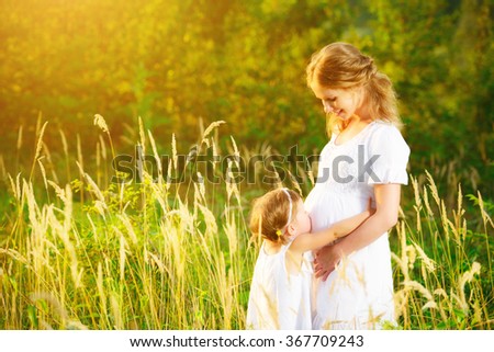 happy family, a pregnant mother and daughter little girl child in the summer  meadow with yellow flowers