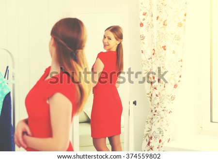 young woman in a red dress looks in the mirror