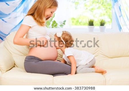 happy family. Pregnant mother and baby daughter kissing relaxing and playing on the sofa at home