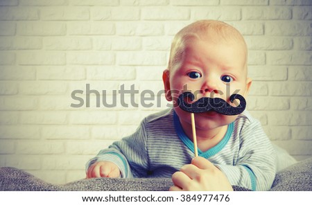 funny baby with a mustache on the brick wall background