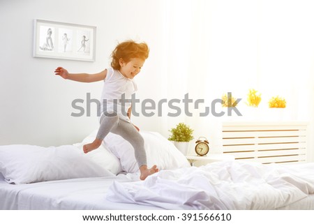 happy child girl having fun jumps and plays bed