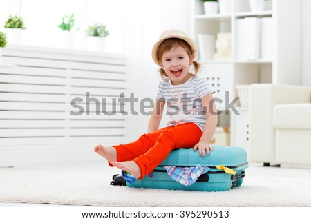 happy child girl tourist packs clothes into a suitcase for travel, vacation
