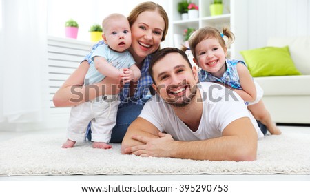 happy family mother, father and two children playing and cuddling at home on floor