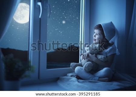child little girl at the window dreaming and admiring the starry sky at bedtime night