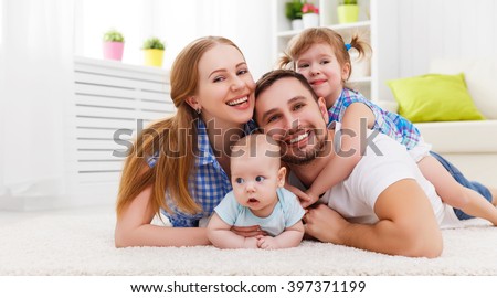 happy family mother, father and two children playing and cuddling at home on floor