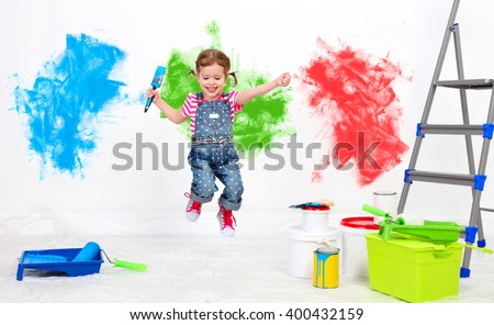 happy funny child girl doing repairs, jumping and paint the wall at home
