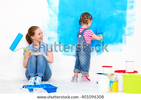 happy family mother and child daughter making repairs, paint the wall at home