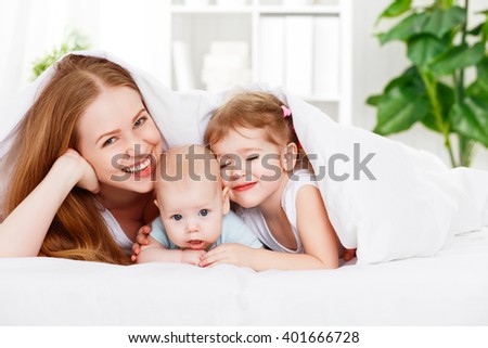 happy family mother and two children, son and daughter in bed playing  under  blanket