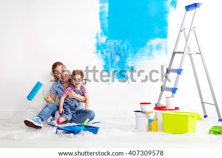 happy family mother and child daughter making repairs, paint the wall at home
