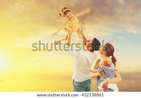 happy family of father, mother and two children, baby son and daughter on  the beach at sunset