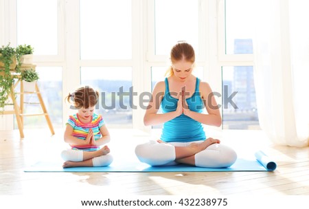 family mother and child daughter are engaged in meditation and yoga, exercise at home