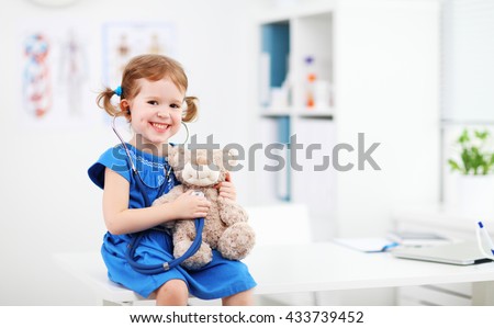 Child girl playing doctor with a teddy bear