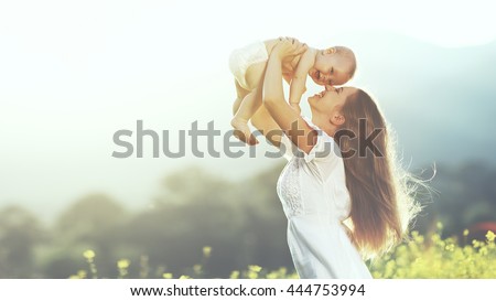 happy harmonious family outdoors. mother throws baby up, laughing and playing in the summer on the nature