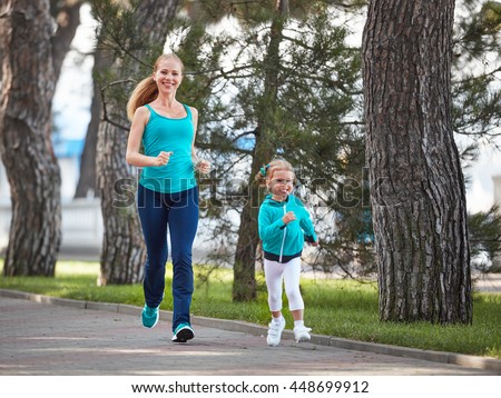 sports family mother and child daughter are engaged in running and athletics in the summer in the park