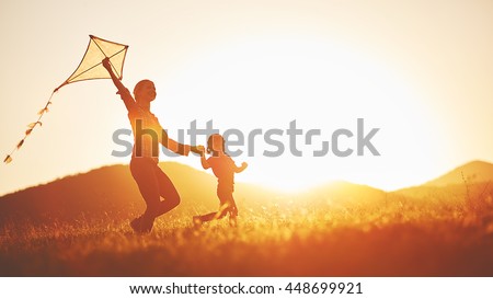 happy family mother and child run on meadow with a kite in the summer on the nature
