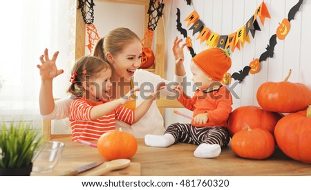Happy family of mother and children prepare for Halloween pumpkins decorate the home