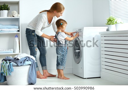 family mother and child girl little helper in laundry room near washing machine and dirty clothes