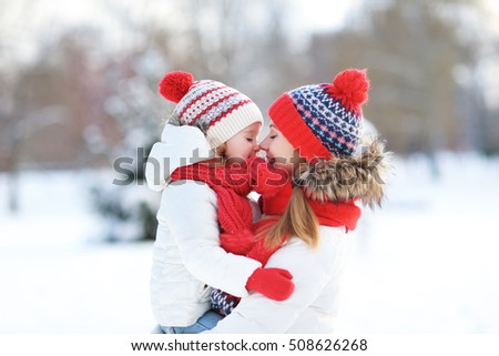 happy family mother and child daughter having fun, playing at winter walk outdoors