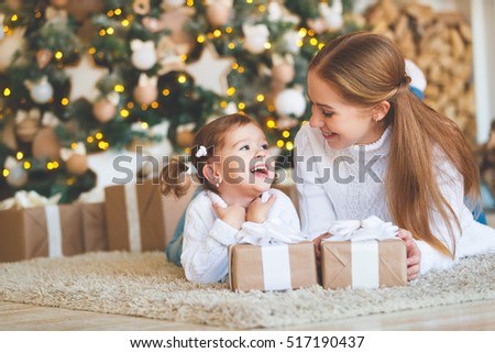 happy family mother and child daughter on Christmas morning at the Christmas tree with gifts