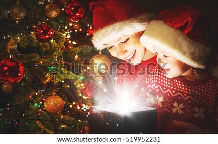 happy family mother and child daughter with magical gift from the Christmas tree