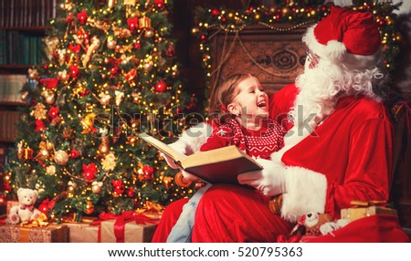 happy child girl hugging Santa reading book and laughs