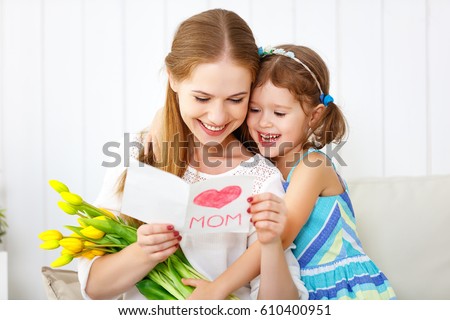Happy mother\'s day! Child daughter congratulates moms and gives her a postcard and flowers tulips