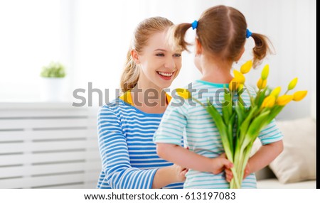 Happy mother's day! Child daughter congratulates moms and gives her a postcard and flowers tulips
