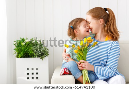 Happy mother\'s day! Child daughter congratulates moms and gives her a postcard and flowers tulips