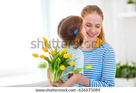 Happy mother\'s day. Child daughter congratulates moms and gives her a postcard and flowers tulips