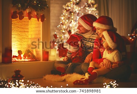happy family father mother and children sitting by fireplace on Christmas Eve